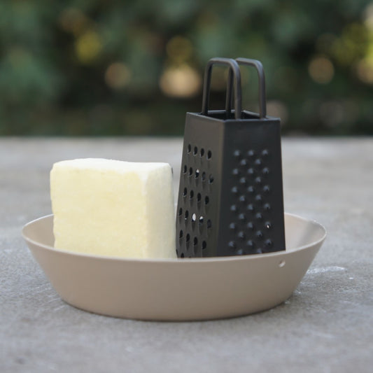 Modern metalen schaaltje in zandkleur voor amberblokjes met een decoratieve zwarte rasp van Rimisa