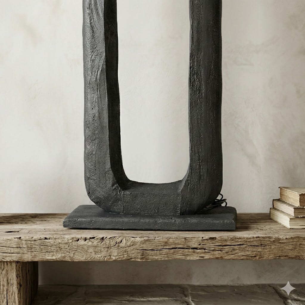 Close-up van de zwart afgewerkte, rechthoekige By Mooss vloerlamp Bali van mango hout, waarbij de voelbare en doorleefde houtstructuur duidelijk zichtbaar is. De lamp rust op een rustieke houten balk met een stapel oude boeken ernaast.