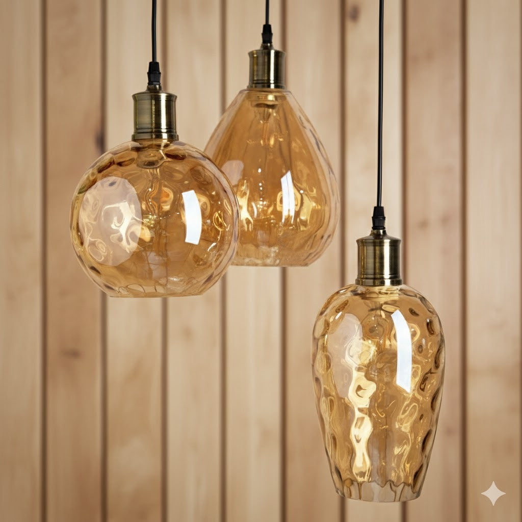 detail en close-up van drie amberkleurige glazen hanglampen met reliëf voor een houten lattenwand van Rimisa.