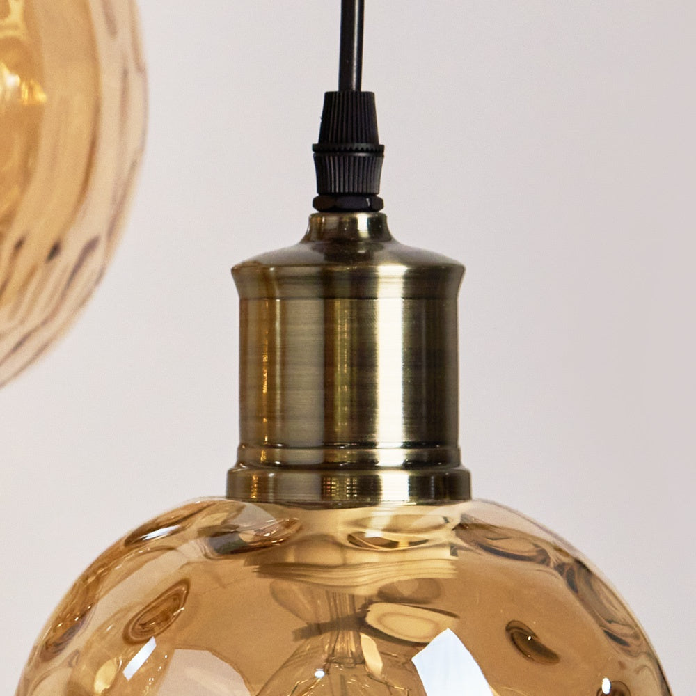 Gedetailleerde close-up van de Verona hanglamp met een zware oudmessing E27 fitting en sfeervol amberkleurig gebubbeld glas van Rimisa.
