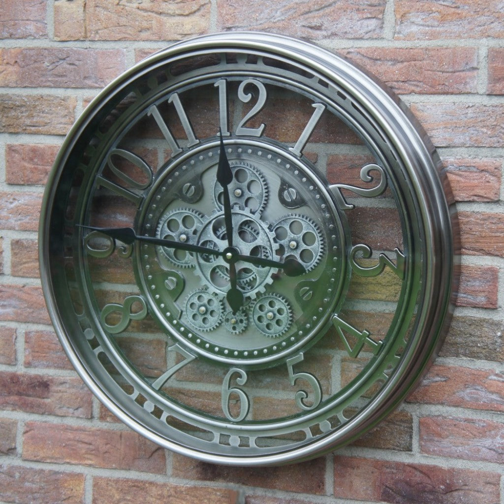 Sfeerbeeld van de zilveren radarklok Levi hangend aan een rustieke gemetselde bakstenen muur.