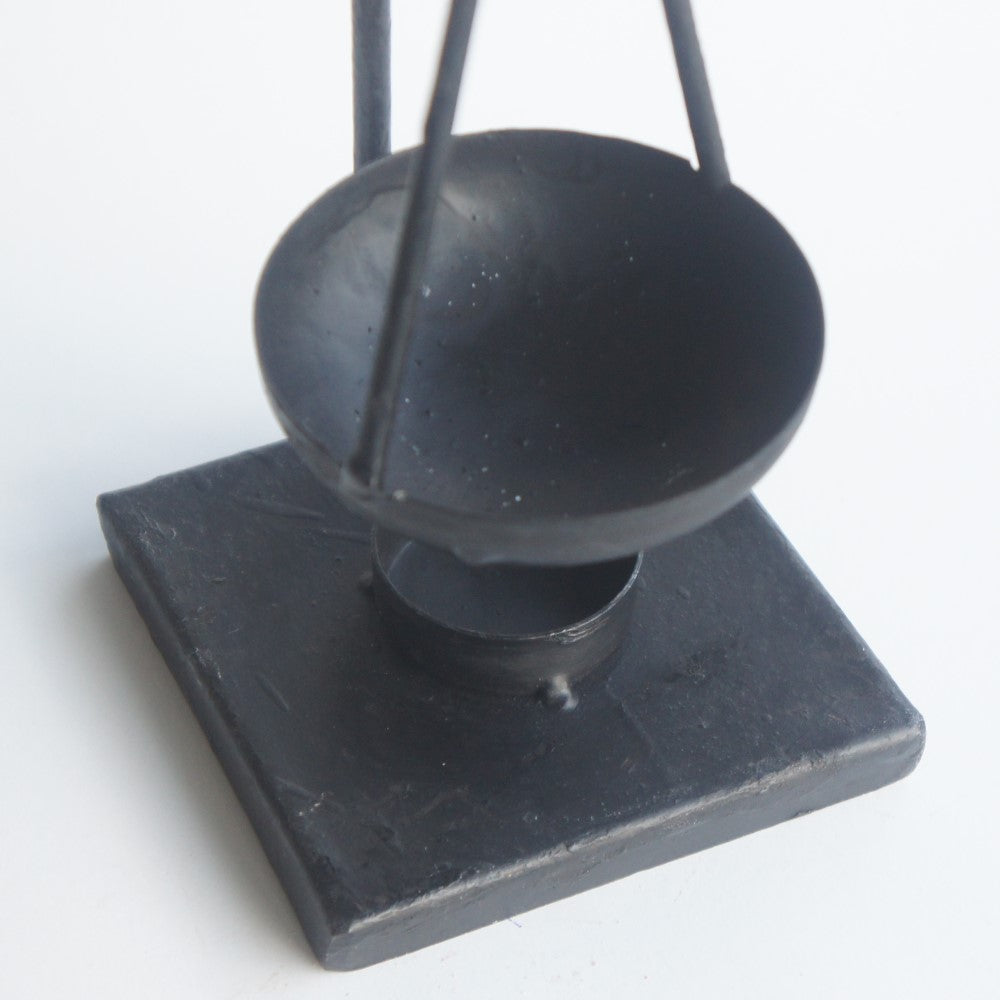 Gedetailleerde weergave van de robuuste afwerking en het schaaltje van de zwarte metalen geurbrander voor amberblokjes van Rimisa