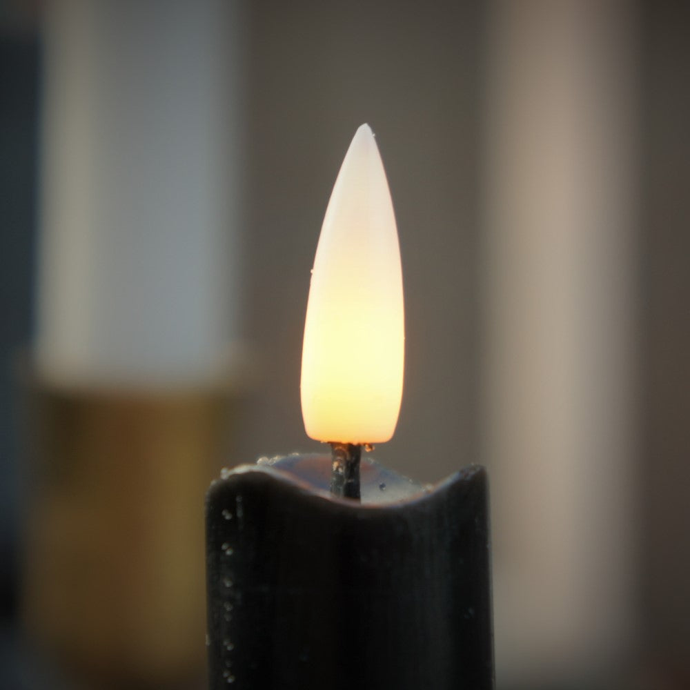 Close-up van de realistische bewegende vlam van een zwarte LED dinerkaars met een warme gloed van Rimisa.