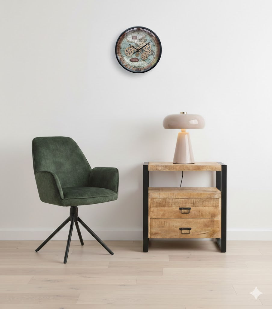 Interieuropstelling met de groene velvet Eetkamerstoel Noah, een mangohouten ladekastje met een moderne tafellamp en een ronde industriële radarklok van 46cm aan een witte wand.
