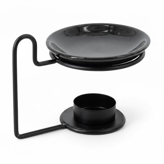 Zwarte keramieken geurbrander disk op een modern metalen frame met natuurlijke schaduw - Rimisa