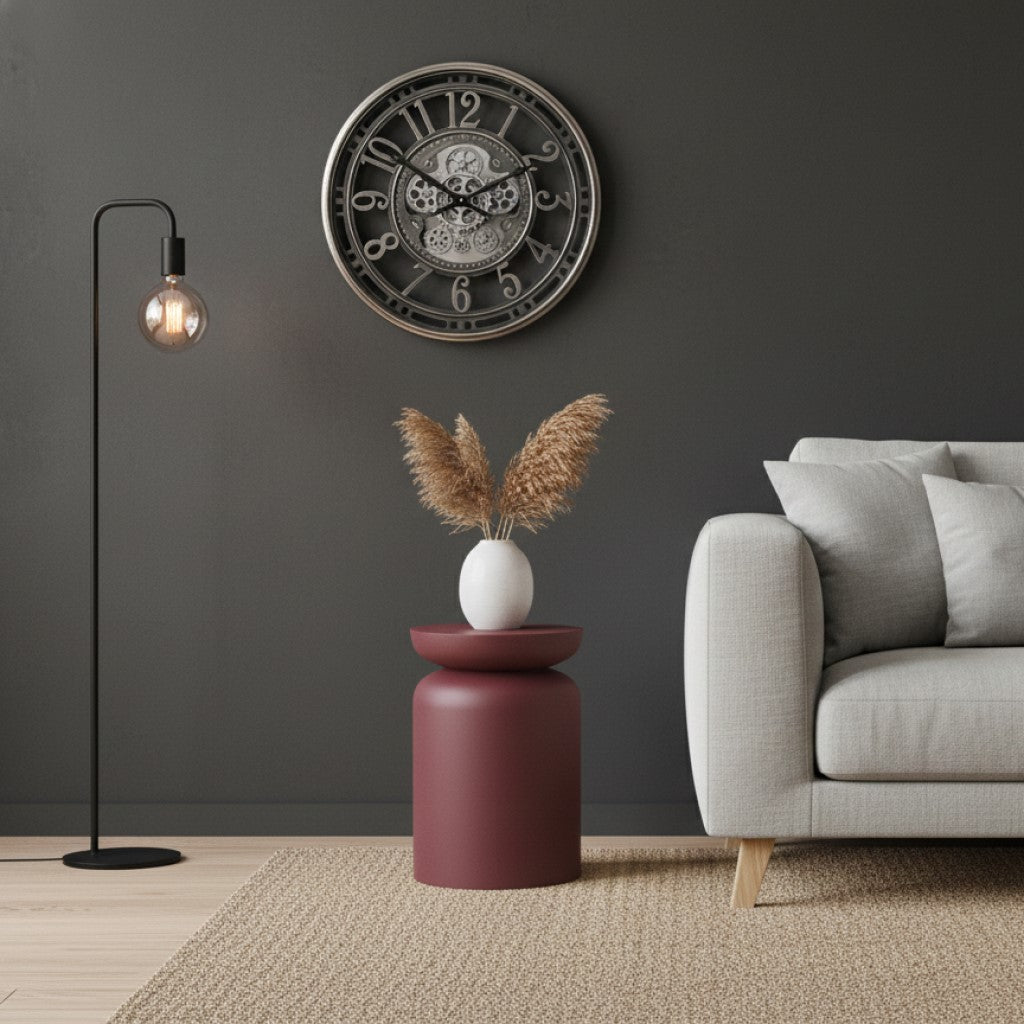 De nikkelen radarklok Levi in een modern interieur met een grijze bank en een bordeauxrode bijzettafel.