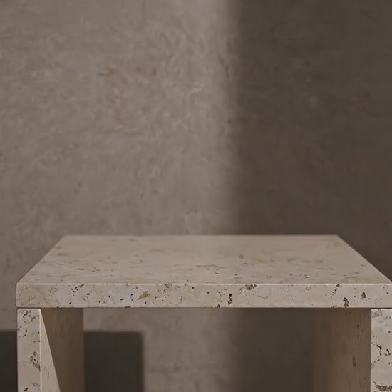 Luxe gouden oplaadbare tafellamp met een glazen kap en warm 2700K licht op een travertijn bijzettafel in een hotel-chique setting, Rimisa.