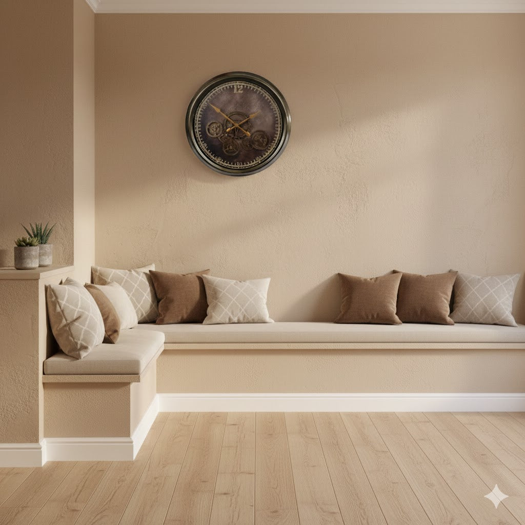 Grote bronskleurige radarklok Vienna met 12 draaiende tandwielen boven een strakke beige zithoek met bruine kussens in een modern klassiek interieur van Rimisa.