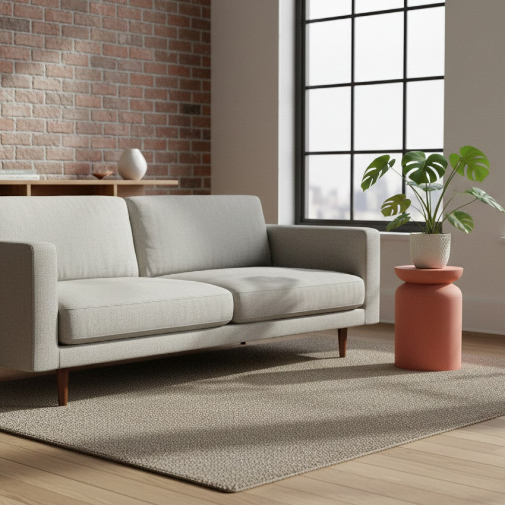 Terracotta bijzettafel van By Moos met een groene plant naast een witte stoffen bank in een industrieel interieur