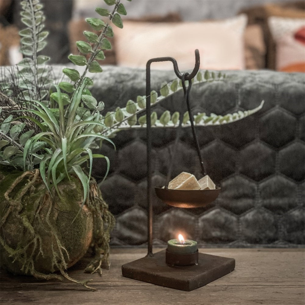 Elegante zwarte metalen geurbrander voor amberblokjes op een sfeervol houten dressoir in een warm en tijdloos interieur van Rimisa